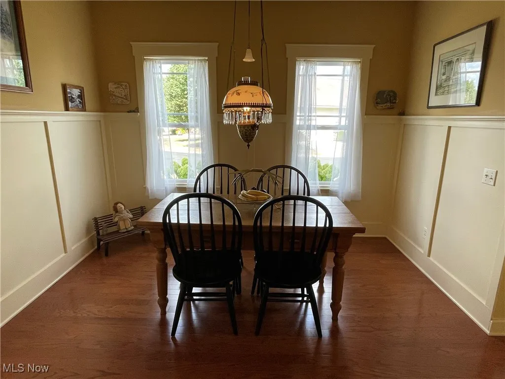 Dining room with a decorative wall, wainscoting, plenty of natural light, and dark wood finished floors