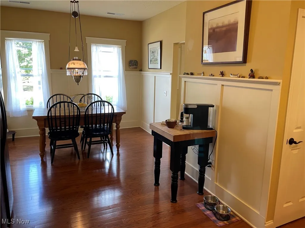Dining space with healthy amount of natural light, dark wood-type flooring, and a wainscoted wall