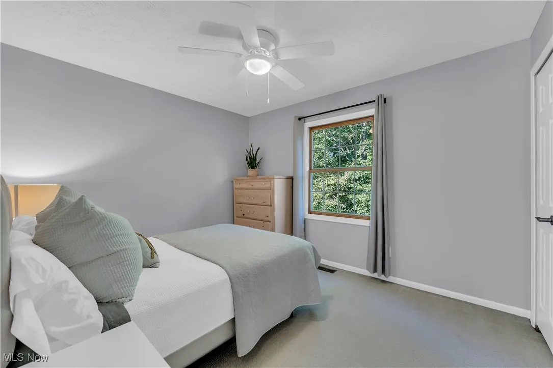 Carpeted bedroom with a ceiling fan and baseboards