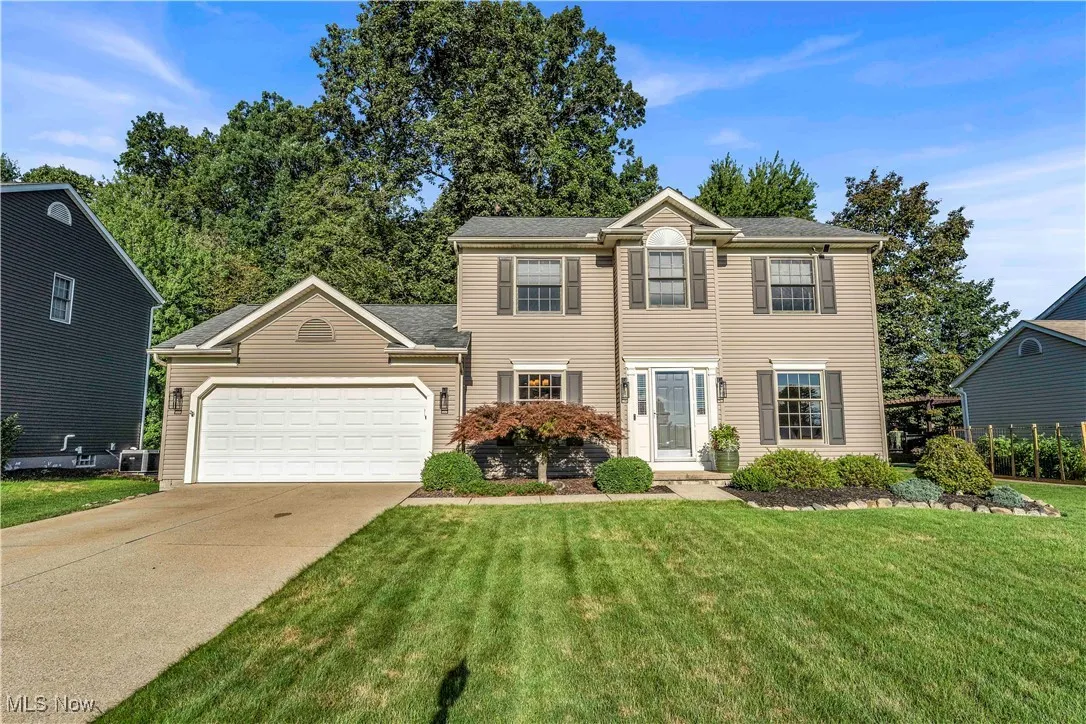 Colonial home with a garage, concrete driveway, and a front lawn