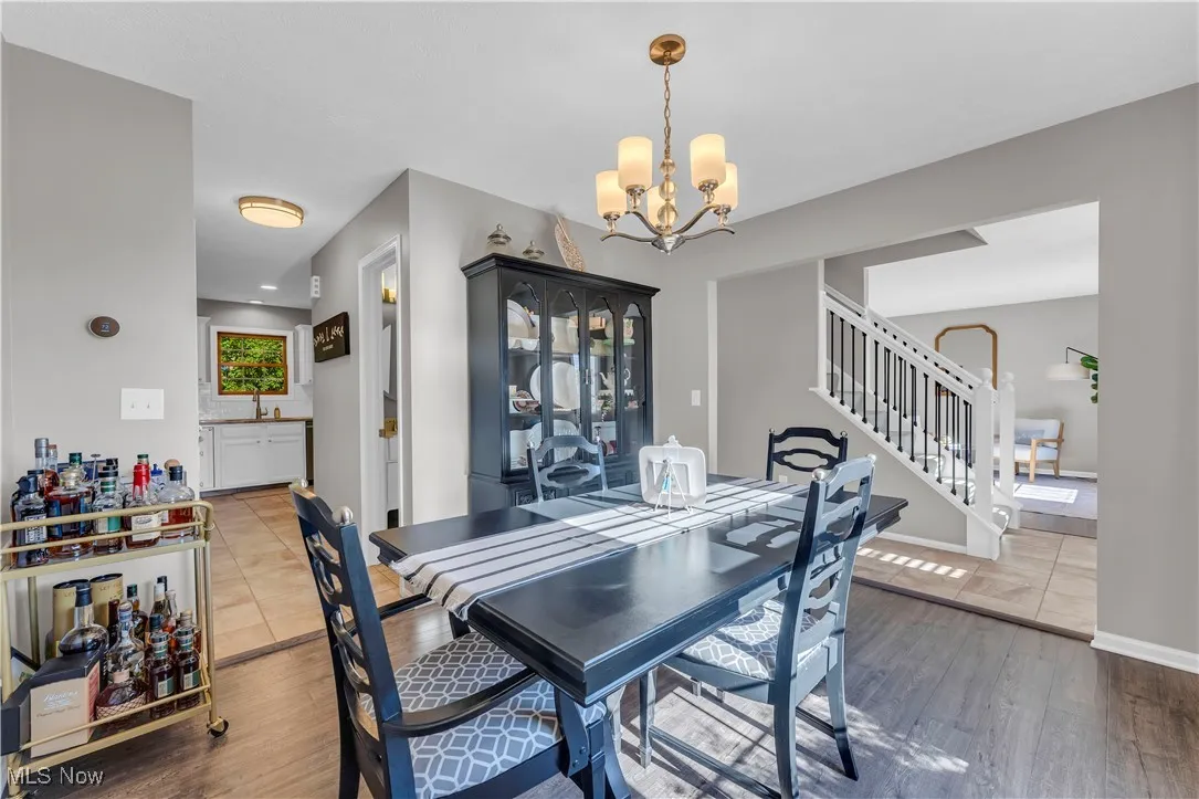 Dining room with dark wood-style floors, a chandelier, and stairs