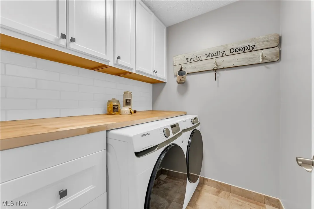 Laundry room with cabinet space, washer and clothes dryer, and a textured ceiling