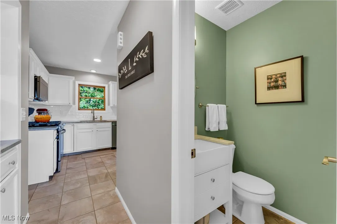 Bathroom featuring light tile patterned flooring, vanity, backsplash, and recessed lighting