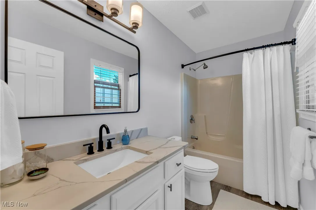 Primary Full bath with shower / tub combo, vanity, and dark wood-style floors
