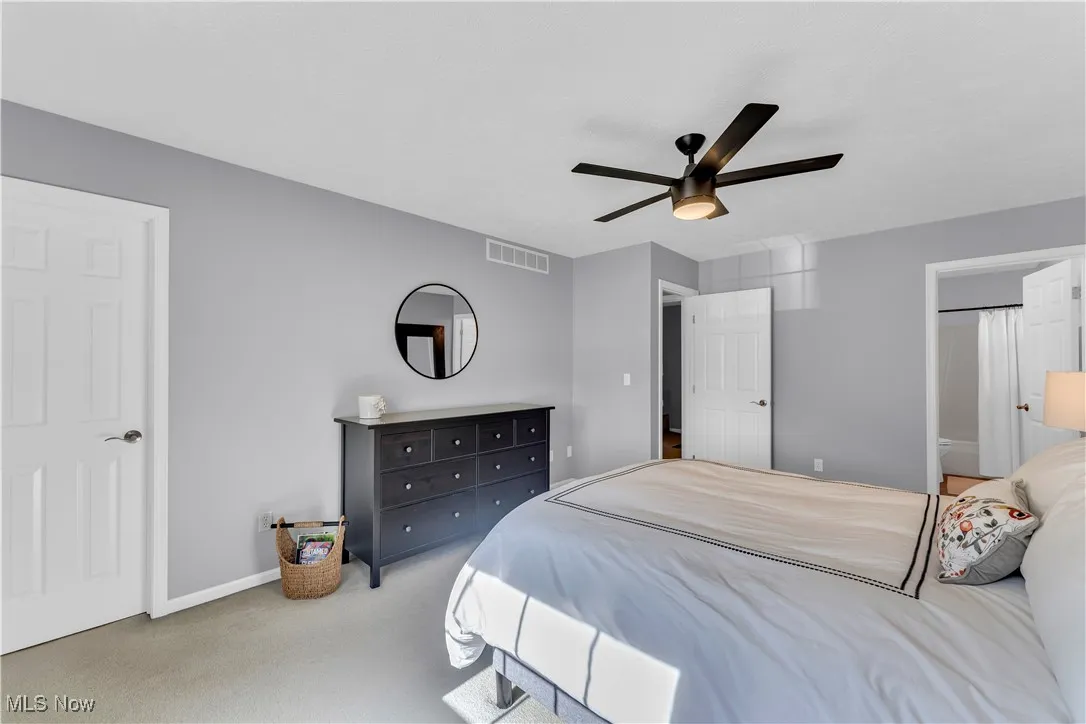 Bedroom featuring carpet floors, ceiling fan, and ensuite bath