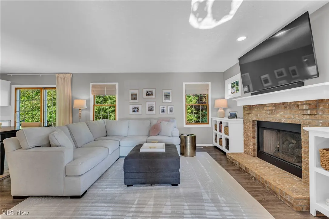 Living area featuring dark wood-style floors, a brick fireplace, and recessed lighting