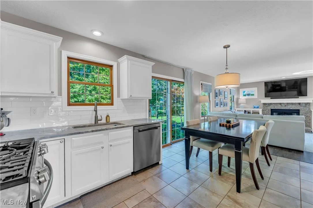 Kitchen featuring stainless steel appliances, light stone countertops, open floor plan, and white cabinets