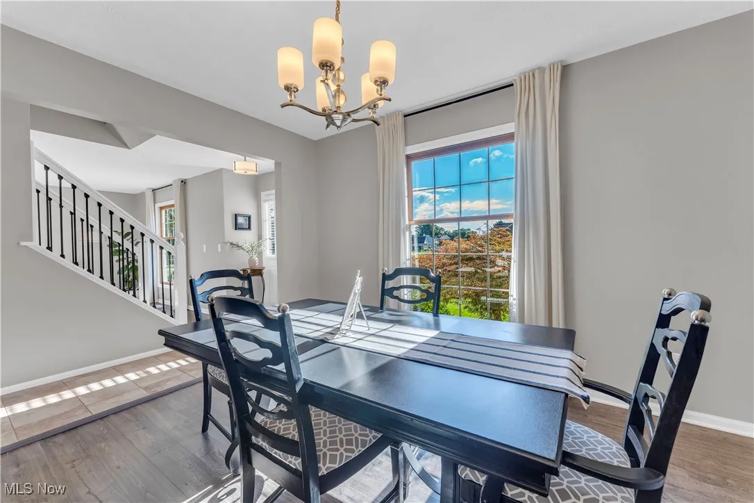 Dining room featuring plenty of natural light, a chandelier, wood finished floors, and stairs