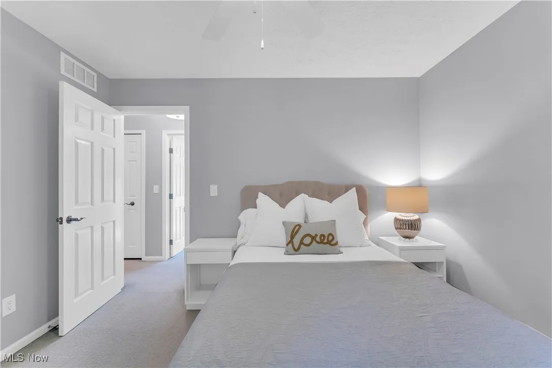 Bedroom with light colored carpet and a ceiling fan