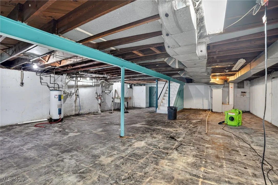 Unfinished below grade area featuring stairway and electric water heater