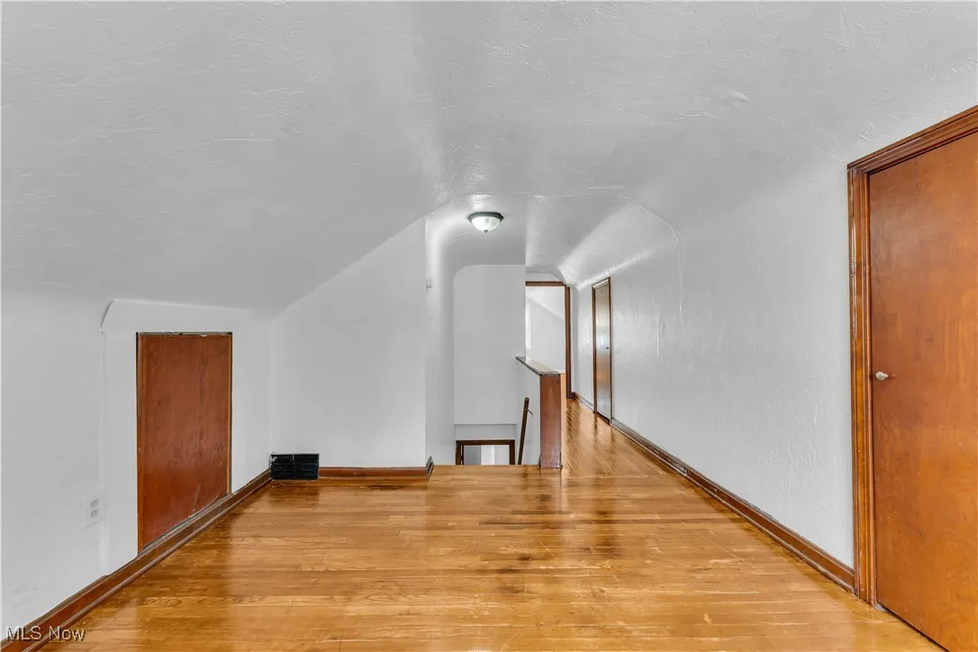Additional living space featuring a textured ceiling, light wood-style floors, and vaulted ceiling