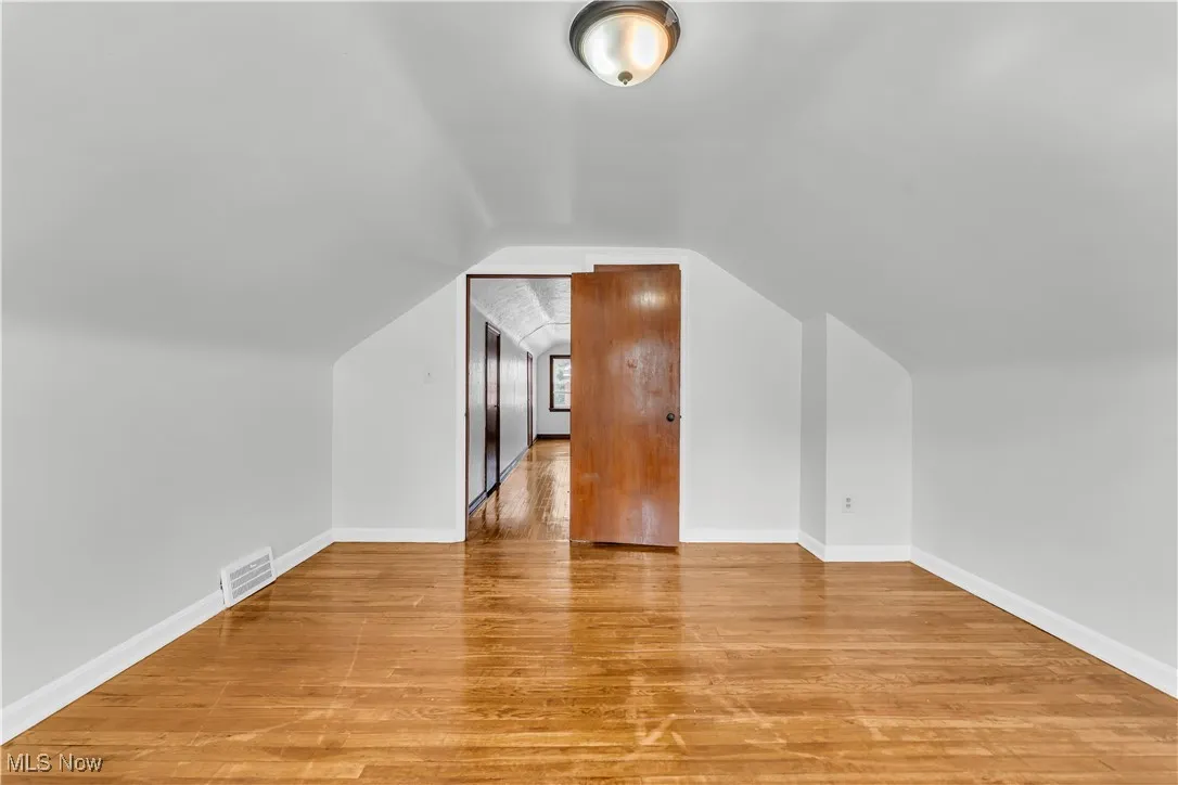 Additional living space with light wood-type flooring and lofted ceiling