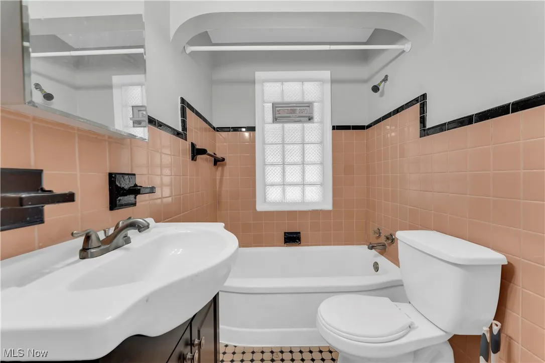 Full bathroom with tile walls,  shower combination, and vanity