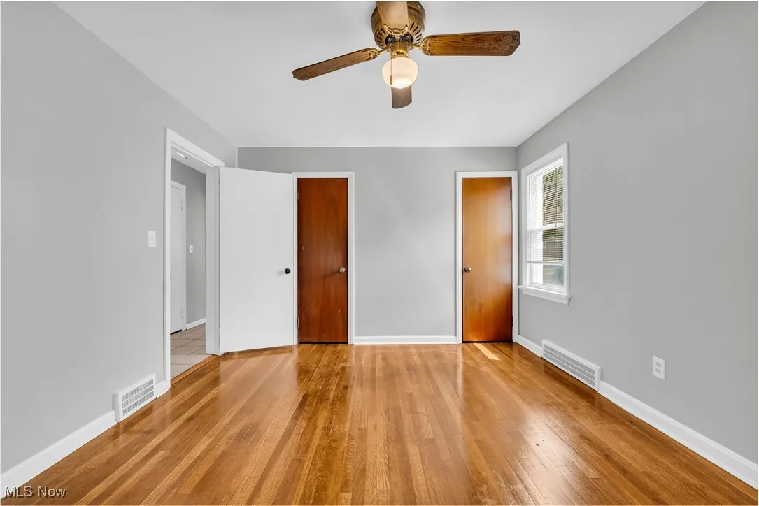 Unfurnished bedroom featuring wood finished floors, multiple closets, and a ceiling fan