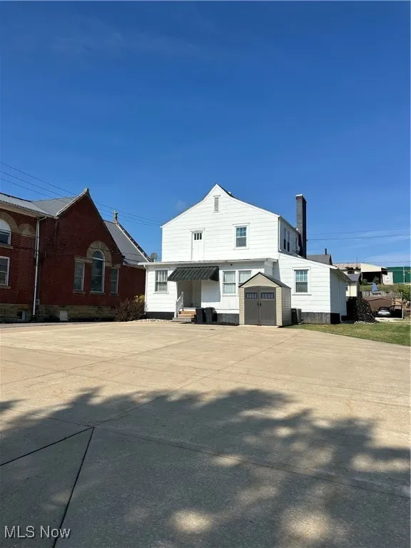 View of back with a storage unit and 10 private parking spaces