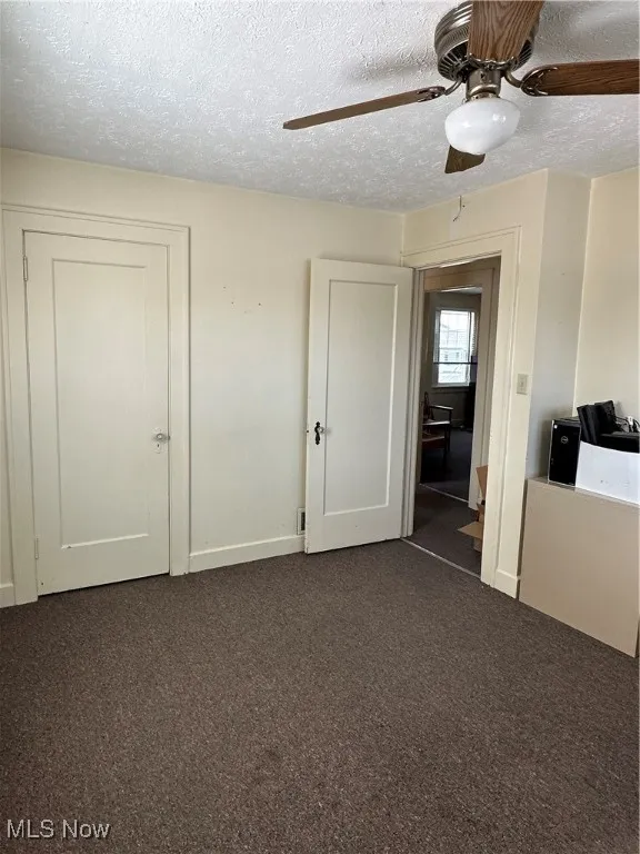Private Office featuring dark carpet, a textured ceiling, and a ceiling fan