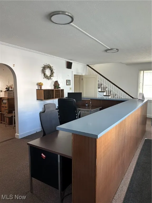 Lobby / Reception with arched walkways, a textured ceiling, and dark carpet