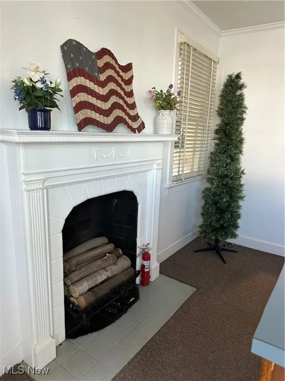 Detailed view of a fireplace, carpet floors, and crown molding in lobby area