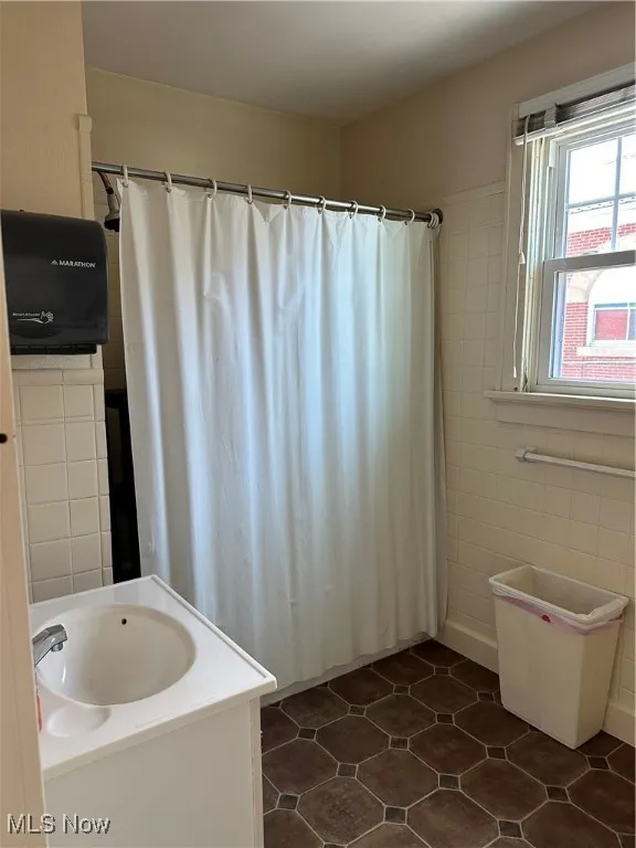 Full bathroom 2nd floor featuring vanity, dark tile patterned flooring, tile walls, and a shower with shower curtain