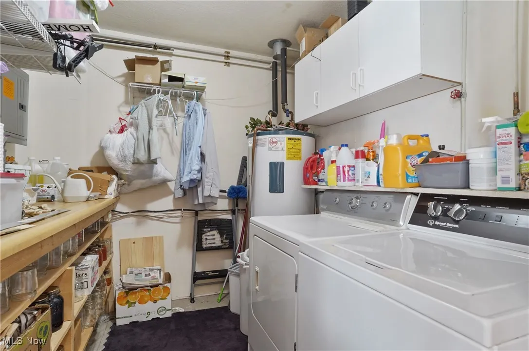 Laundry area with electric water heater, cabinet space, electric panel, and washer and clothes dryer