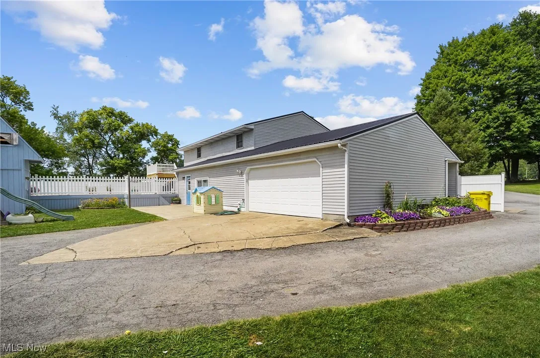 View of side of home featuring driveway, an attached garage, and a metal roof