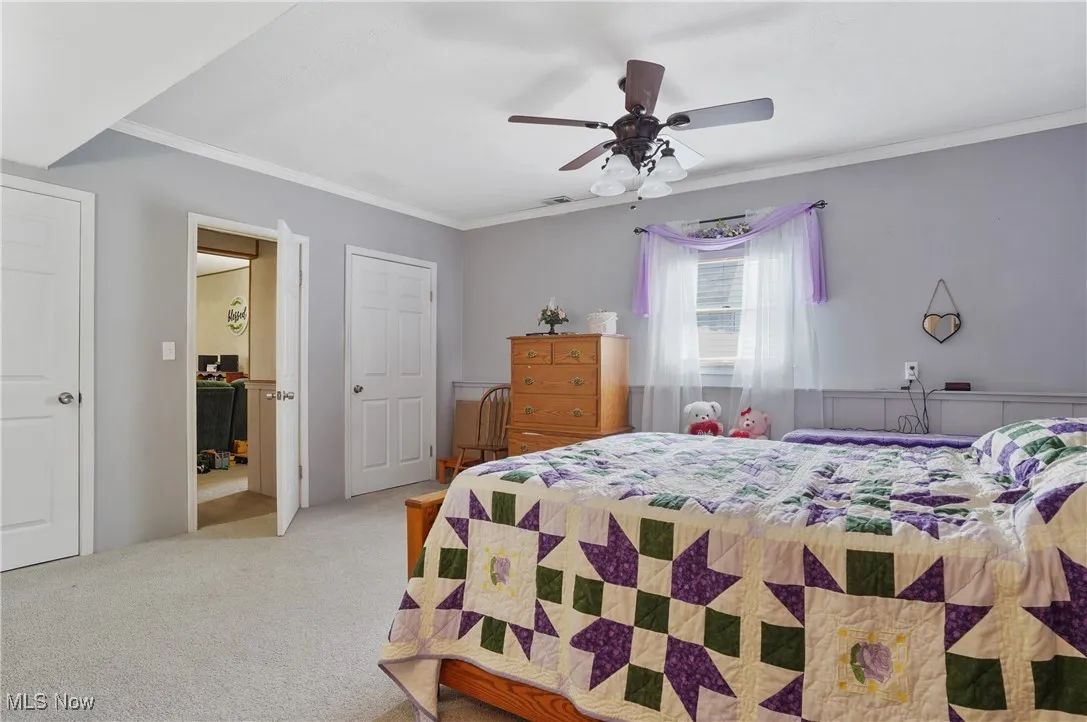 Bedroom featuring crown molding, light carpet, and a ceiling fan