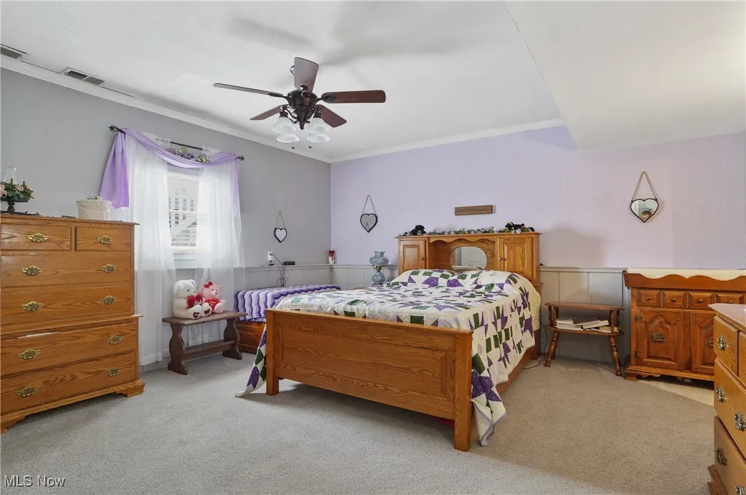 Bedroom with ornamental molding, light colored carpet, and a ceiling fan