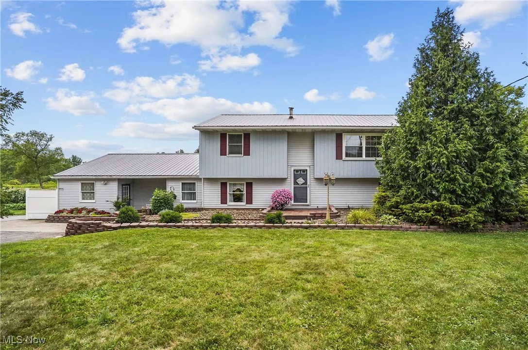 Bi-level home featuring a metal roof and a front lawn