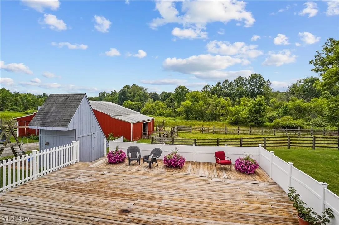 Wooden deck featuring a detached garage, an outdoor structure, and view of scattered trees