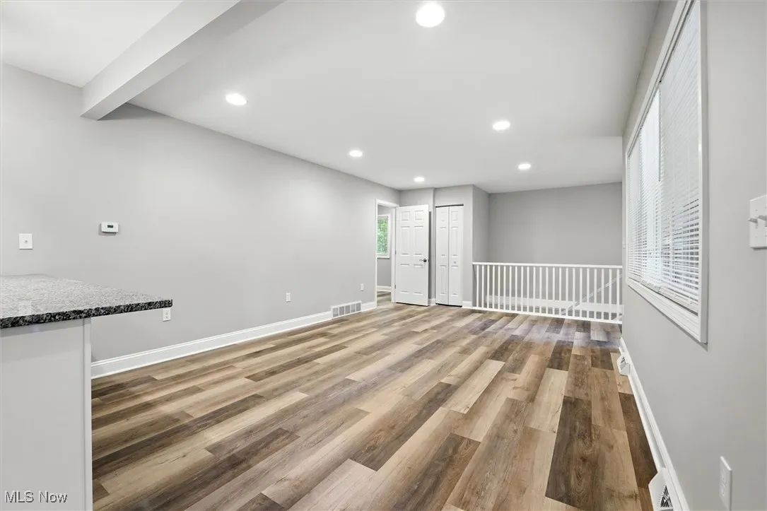 Unfurnished living room featuring recessed lighting, light wood-style flooring, and beamed ceiling