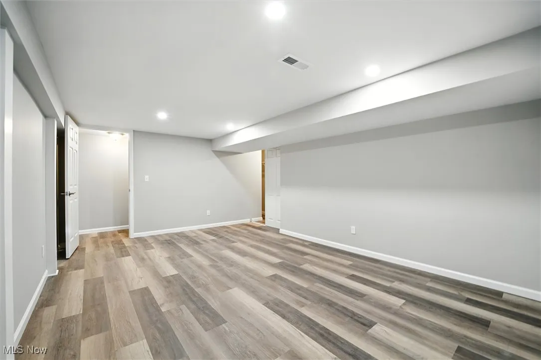 Finished basement with light wood-style floors and recessed lighting