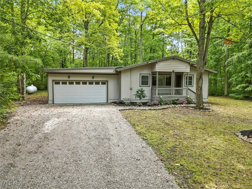 View of front of house with driveway, a garage, a porch, and a front lawn