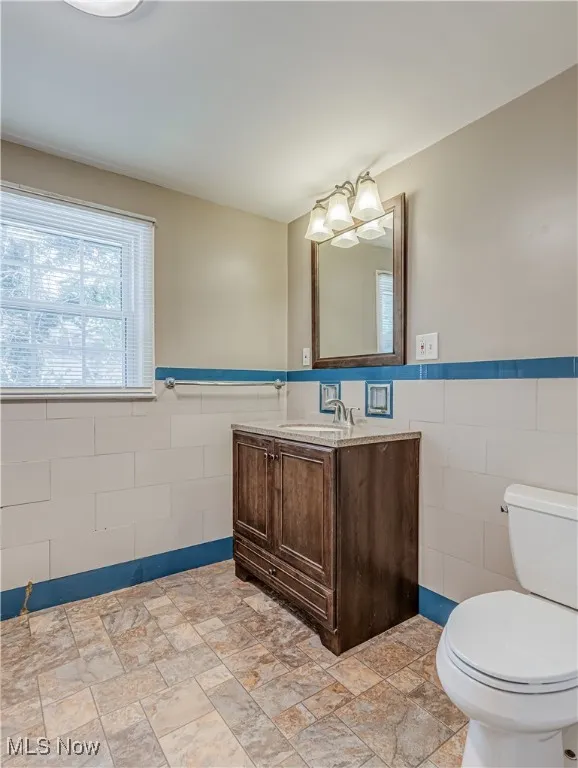 Bathroom with tile walls, a wainscoted wall, and vanity