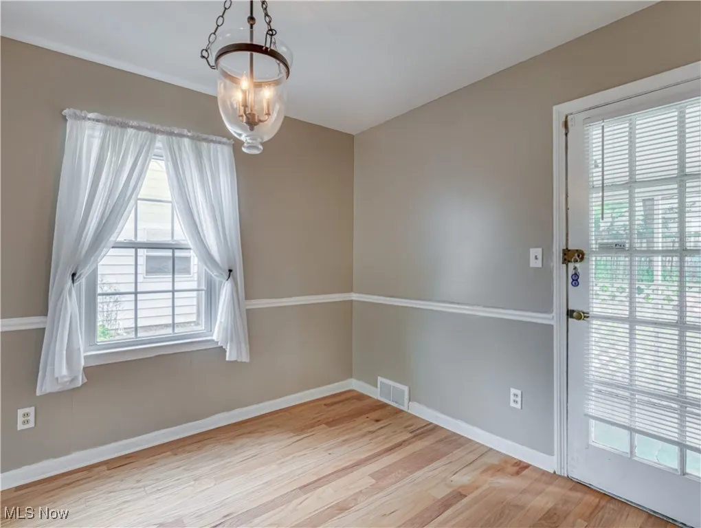 Unfurnished dining area featuring light wood finished floors and a chandelier