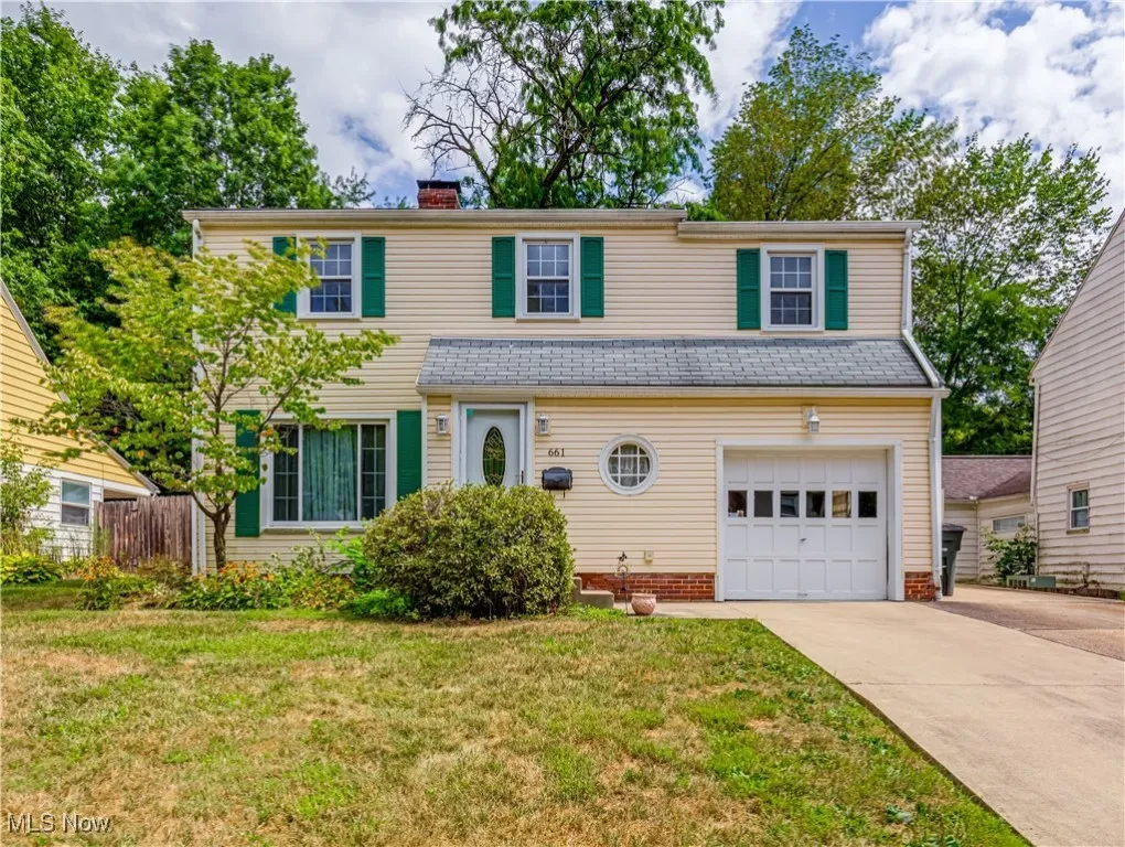 Traditional-style home with an attached garage, driveway, and a chimney