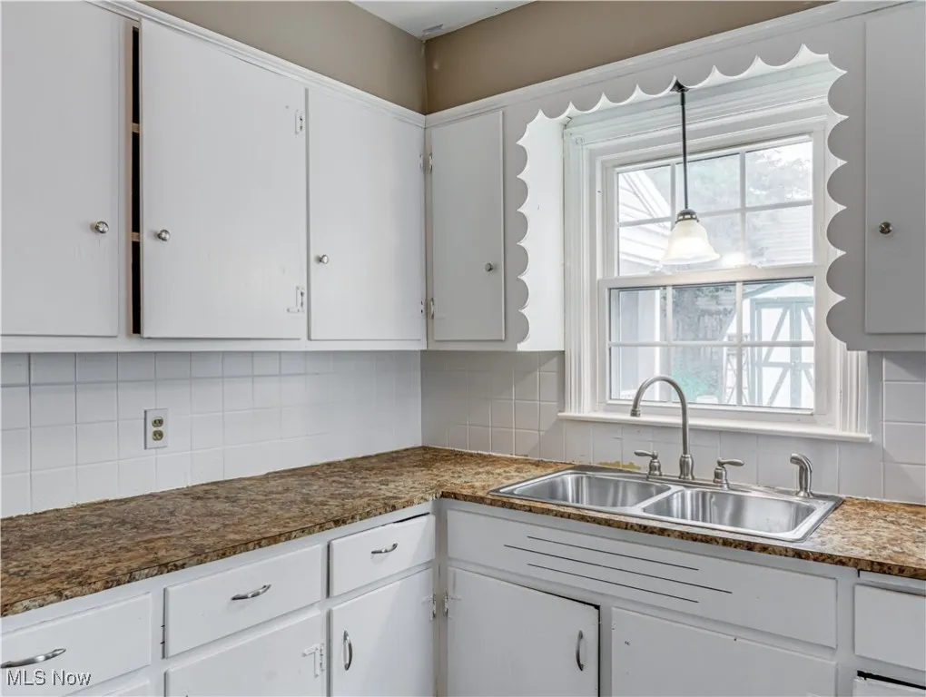 Kitchen featuring backsplash and white cabinetry