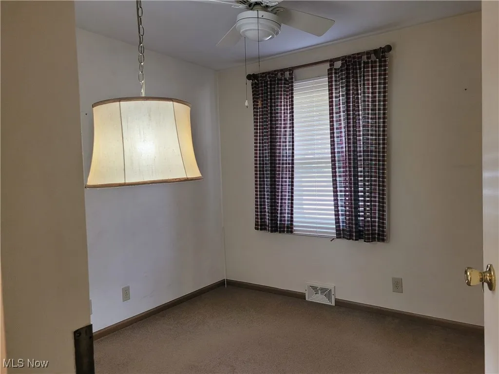 Carpeted spare room with baseboards and ceiling fan