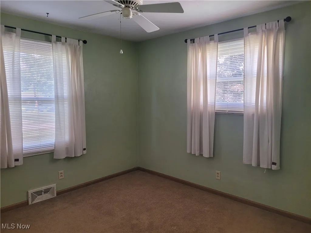 Unfurnished room featuring carpet floors and a ceiling fan