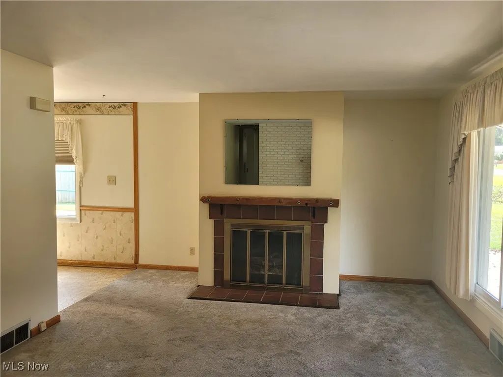 Unfurnished living room featuring a tile fireplace and carpet
