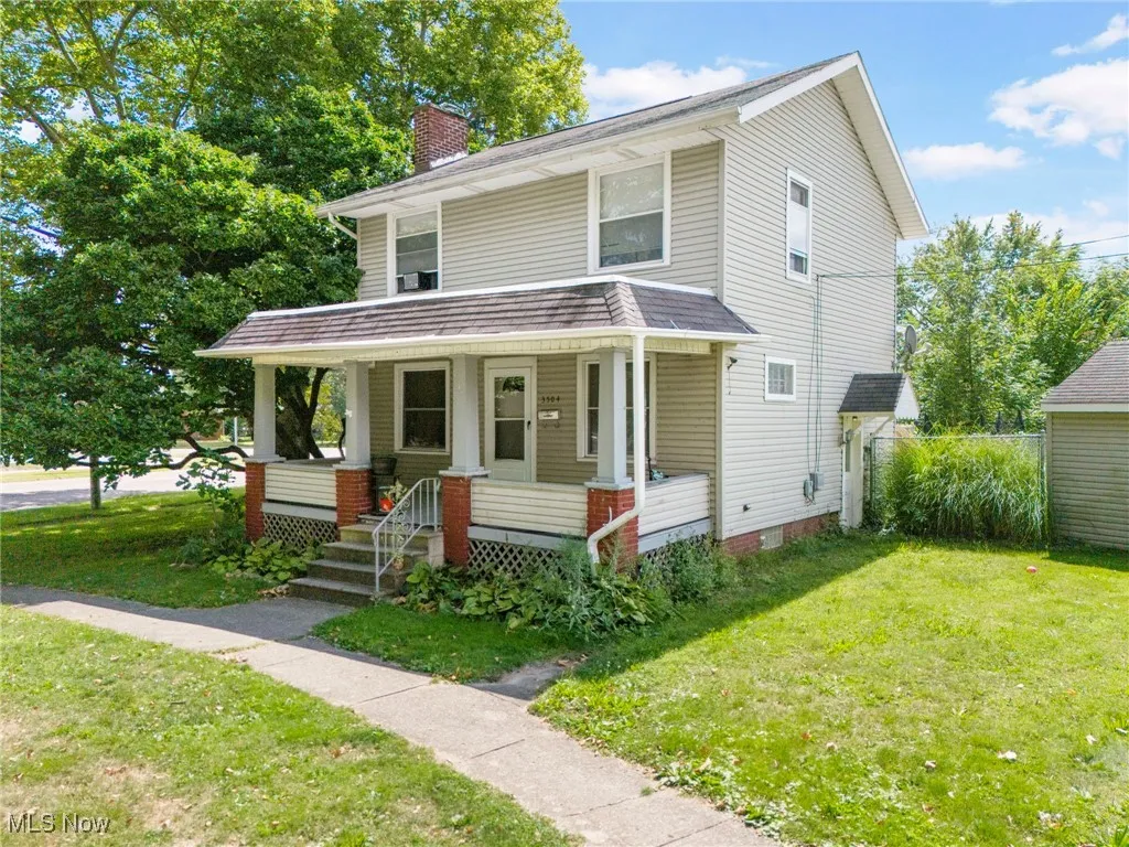 Traditional style home featuring a front lawn, covered porch, and a chimney