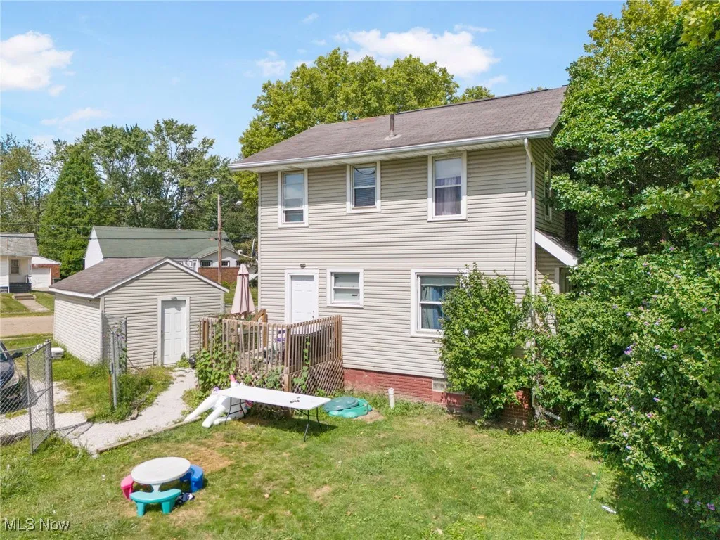 Back of property with an outbuilding and a shingled roof