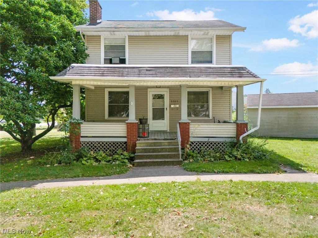 Traditional style home featuring covered porch, a chimney, and a front lawn
