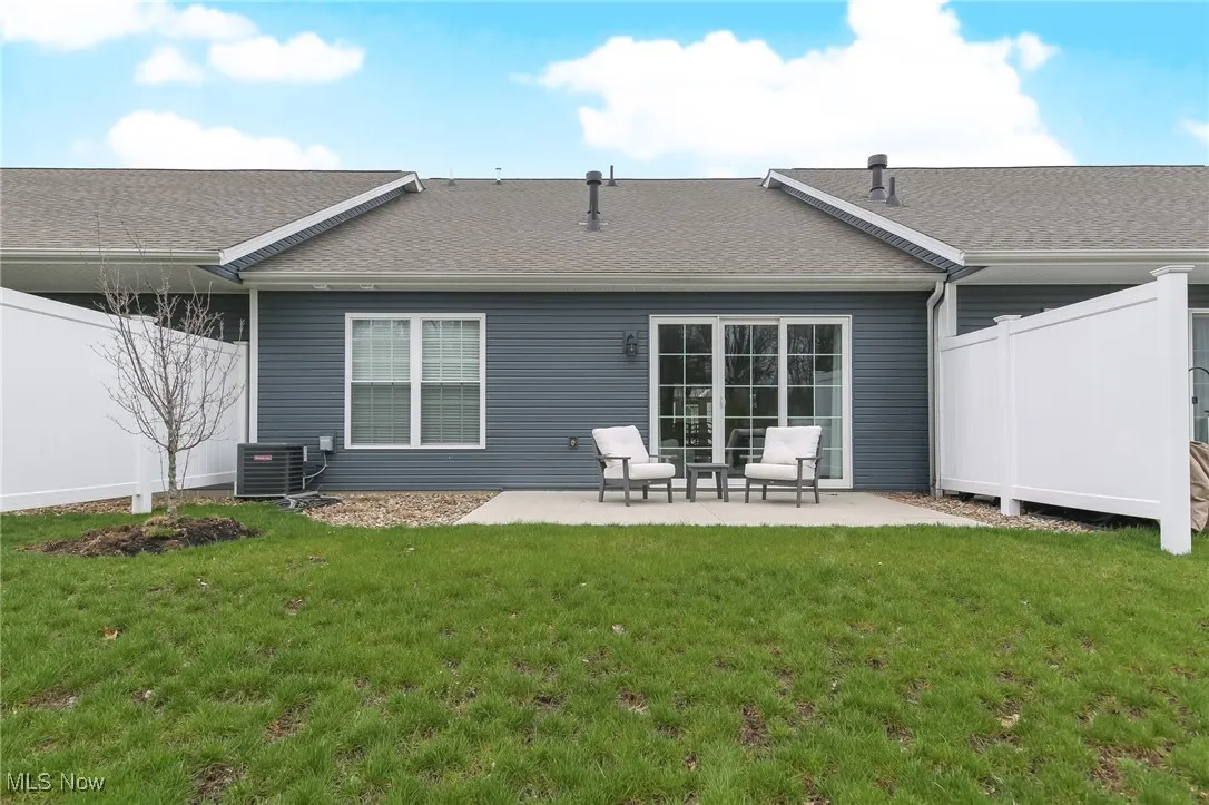 Back of property with roof with shingles and a patio area