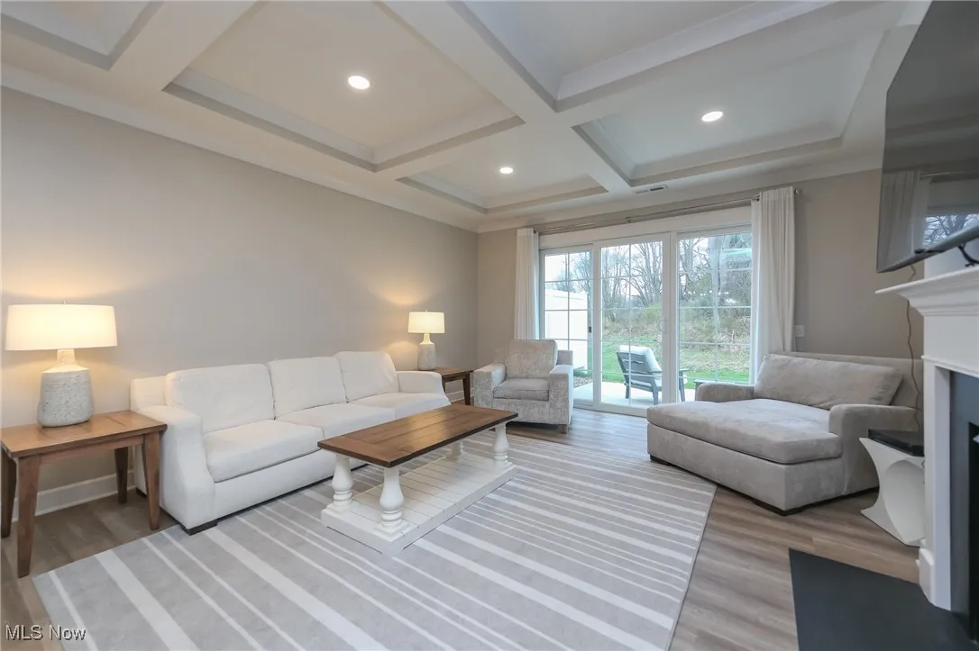 Living area with beamed ceiling, light wood-style floors, coffered ceiling, recessed lighting, and a fireplace