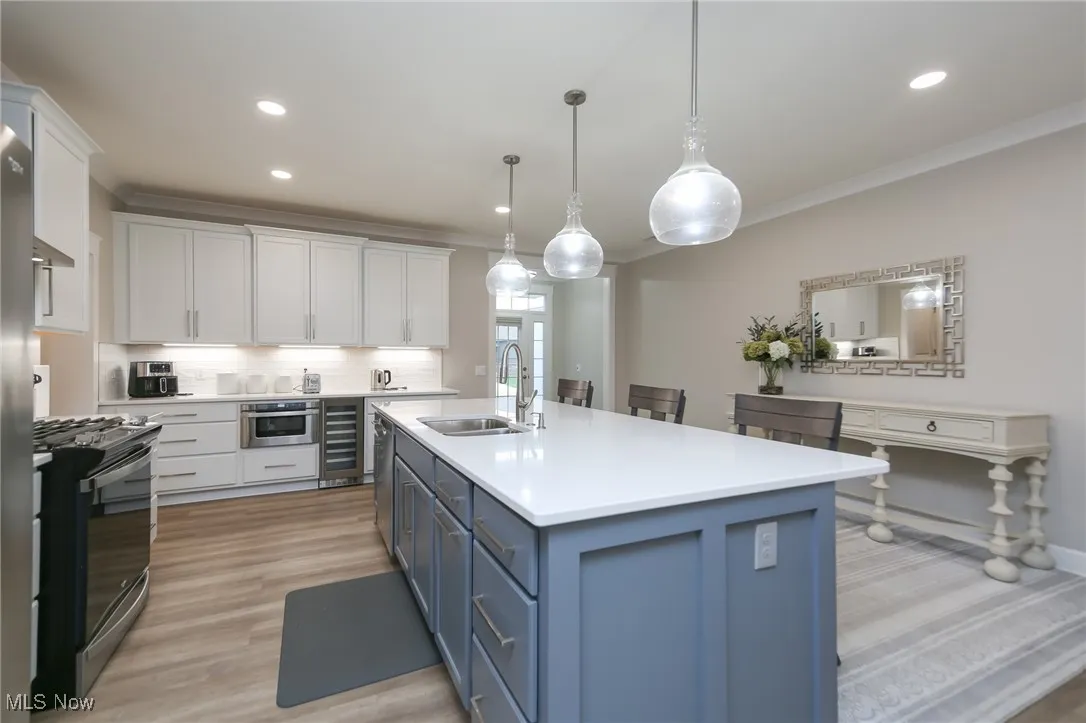 Kitchen with blue cabinets, white cabinetry, pendant lighting, decorative backsplash, and range with gas stovetop