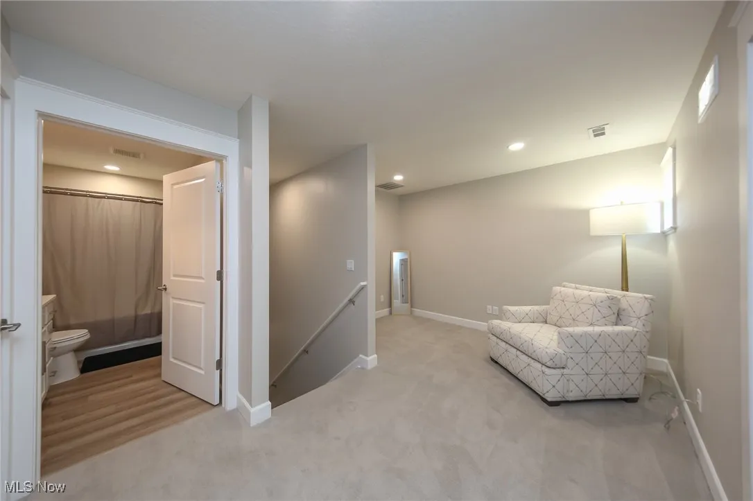 Living area featuring an upstairs landing, light colored carpet, and recessed lighting