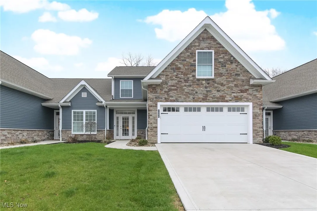Craftsman inspired home with stone siding, a front yard, concrete driveway, and roof with shingles