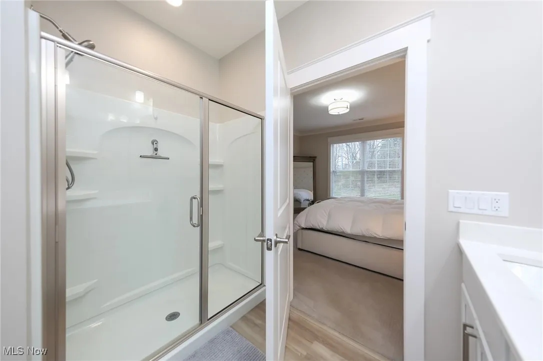 Bathroom with a shower stall, vanity, ensuite bath, and light wood-type flooring