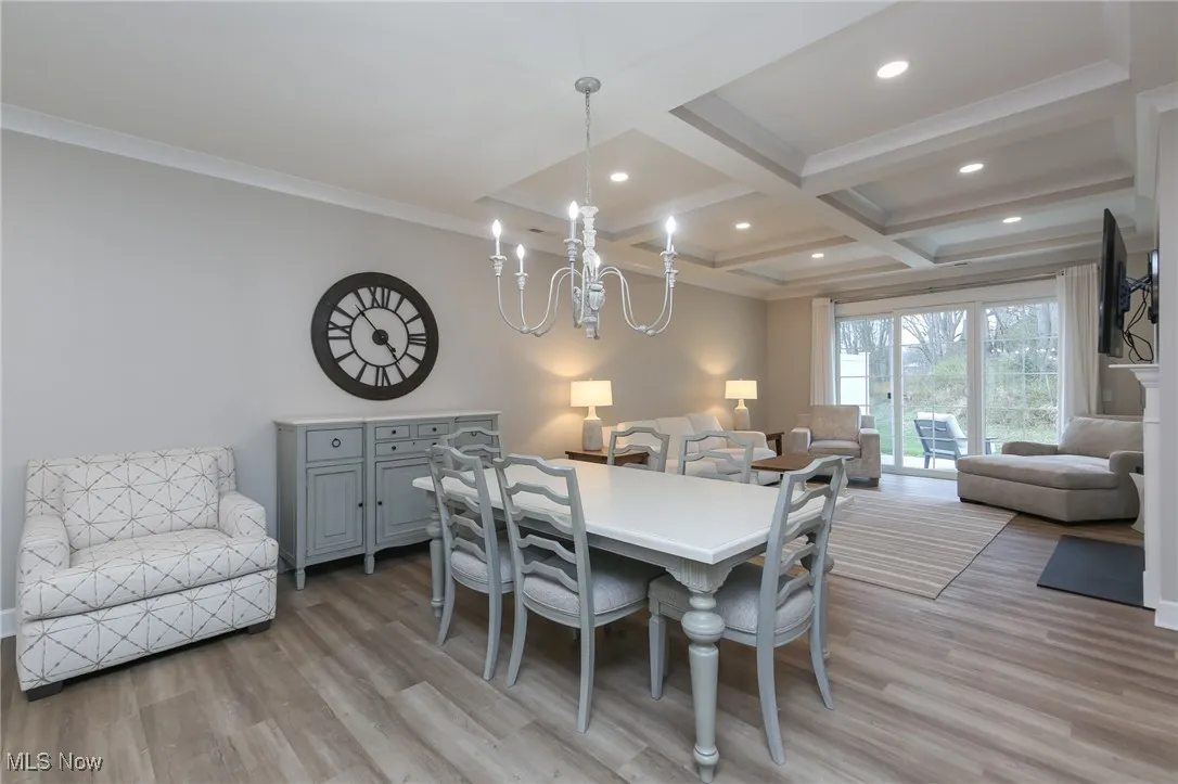 Dining space featuring light wood-style flooring, beam ceiling, coffered ceiling, recessed lighting, and a chandelier