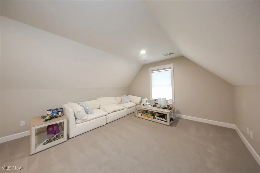 Carpeted living area featuring baseboards and lofted ceiling
